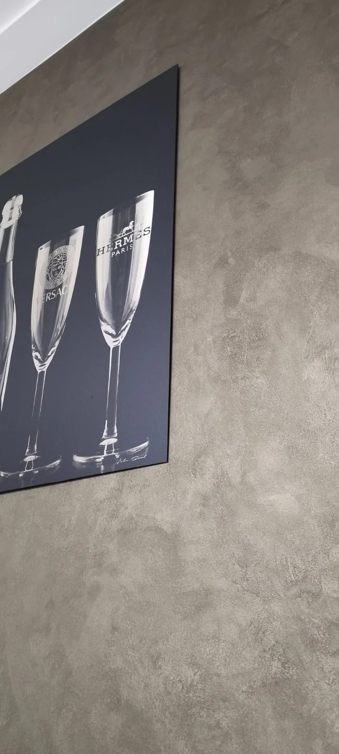 Warme decoratieve wandafwerking met genuanceerde glans naast een zwarte schilderijlijst