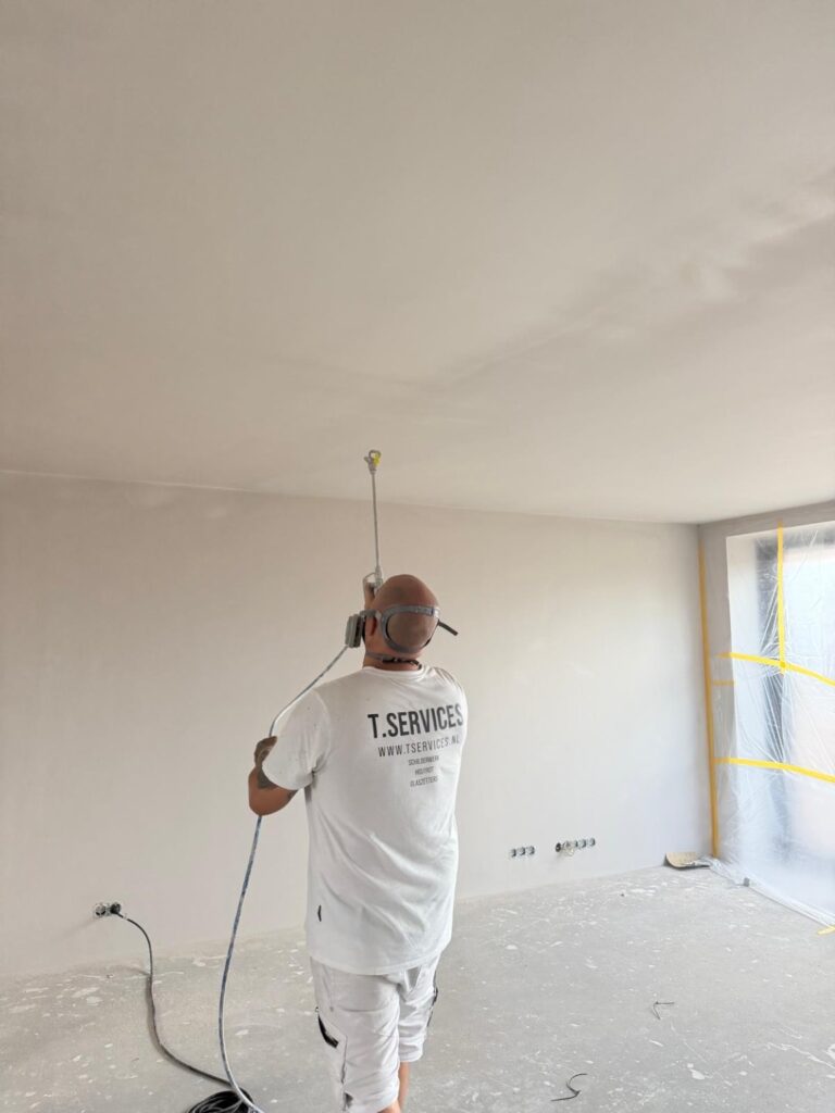 T. Services aan het werk: latex spuiten van een plafond in een afgeplakte binnenruimte